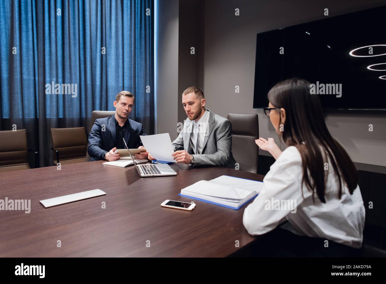 Jeune entreprise, l'entreprise créative des gens de différentes races et de l'âge se rassembler dans une salle de réunion dans l'intérieur de bureau moderne sombre, vivously à discuter. Banque D'Images