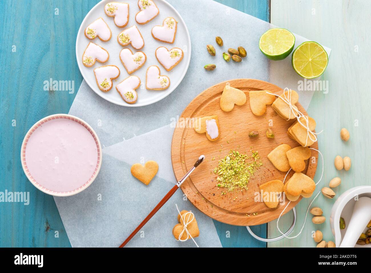 Se préparer pour la Saint-Valentin. Sablés épicés glacé en plein cœur de formes, orné de la chaux-framboise écrasée de givrage et de pistaches. La wifi Banque D'Images