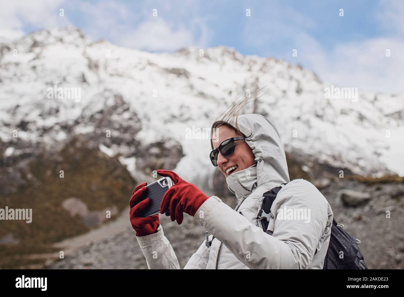 Femme randonneur utilise la caméra de téléphone cellulaire lors de journées venteuses en montagne. Banque D'Images