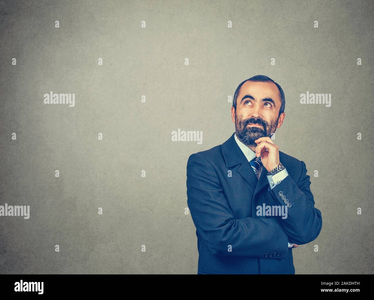 La pensée. Homme barbu avec costume foncé bleu shirt tie regarder toucher le menton, à la recherche. Yeux expressifs. Bras croisés. Organe d'expression. G lumineux isolés Banque D'Images