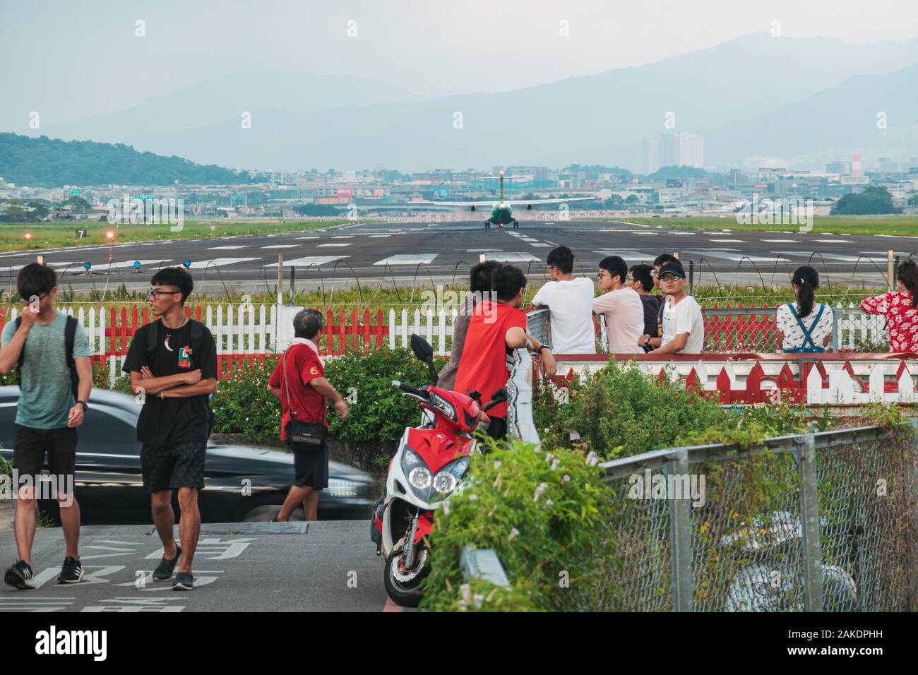 Un avion Uni Air s'aligne sur la piste de l'aéroport de Songshan, tandis qu'une foule de personnes regardent de l'extérieur de la clôture Banque D'Images