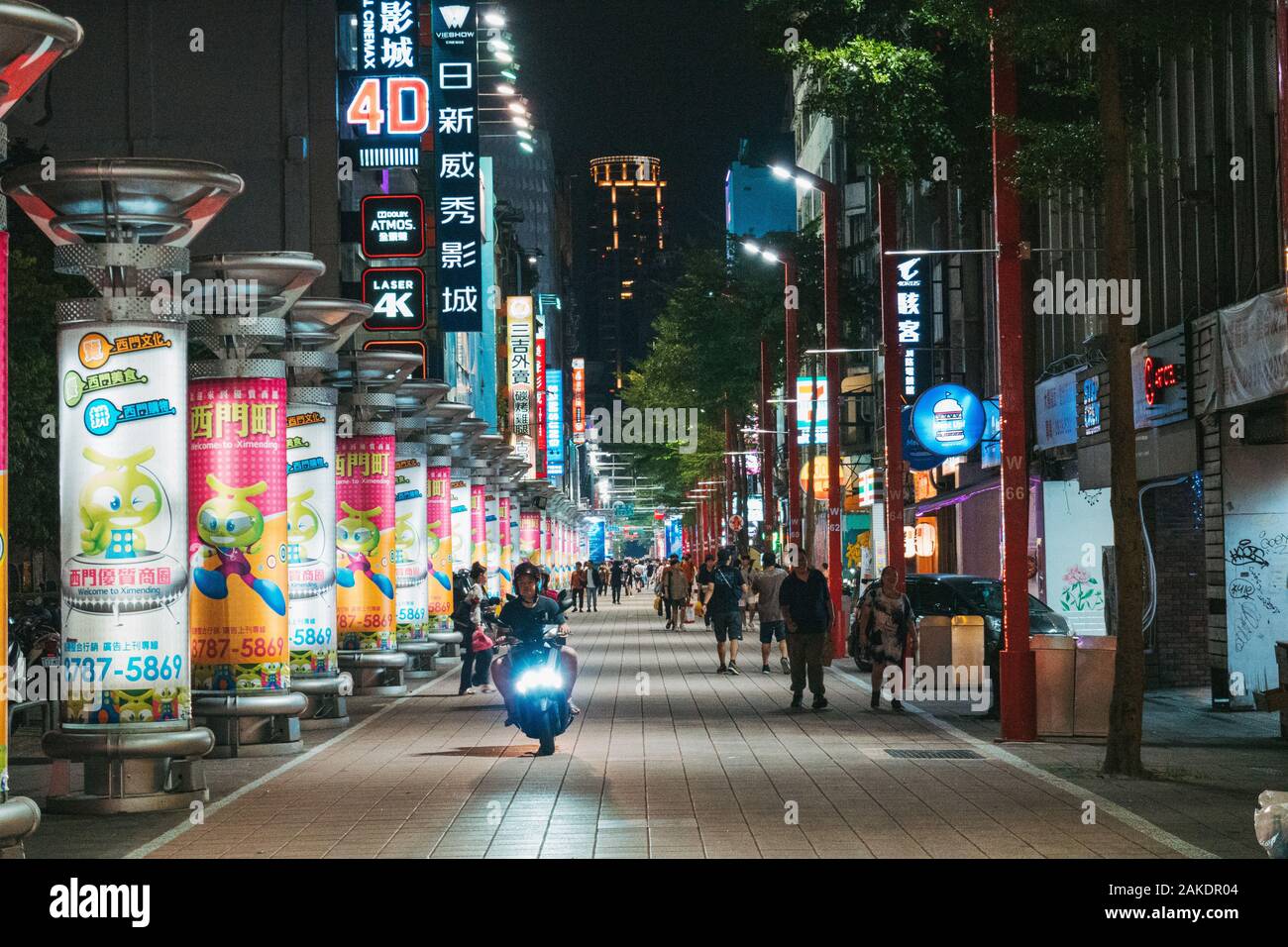 Un scooter descend dans un centre commercial piétonnier rempli de publicités illuminées la nuit, dans le centre de Taipei, à Taïwan Banque D'Images