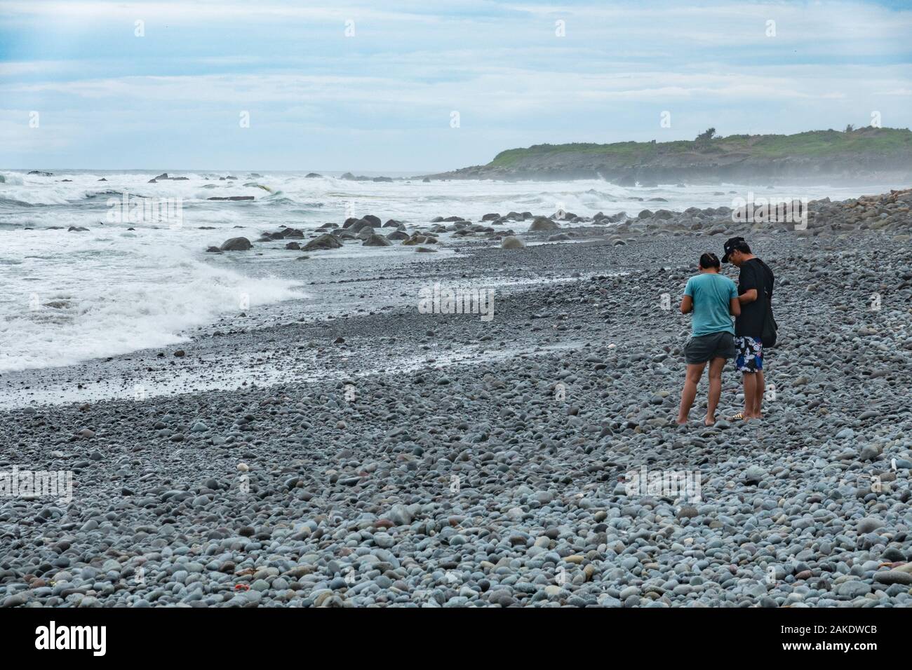 Deux touristes sur la plage de Dulan après un cyclone passé à proximité de la veille, l'envoi d'énorme houle s'écraser sur le rivage Banque D'Images