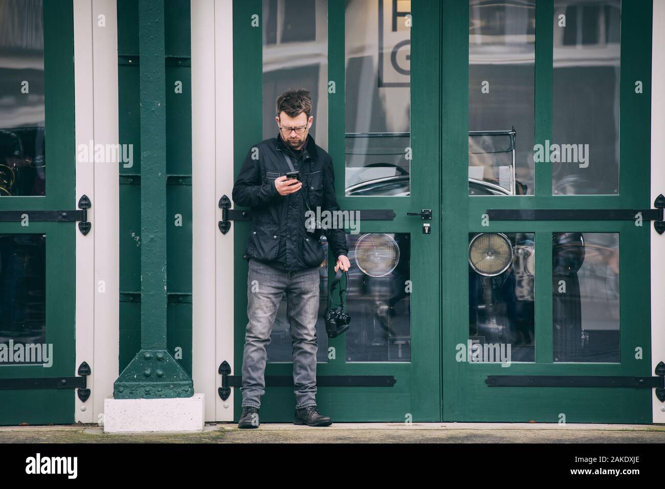 Photographe sur le téléphone en face d'un atelier à l'Bicester janvier Heritage Centre dimanche scramble event. Bicester, Oxfordshire, Angleterre. Banque D'Images