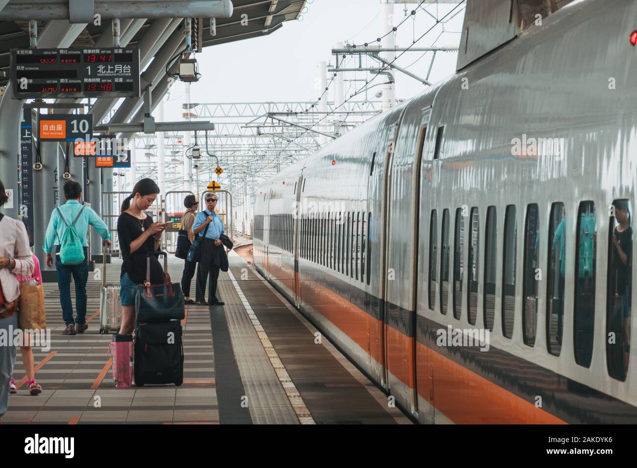 Une femme vérifie son téléphone lors de l'attente sur la plate-forme d'un Taiwan High Speed Rail bullet train, à la gare de Tainan, Taiwan Banque D'Images