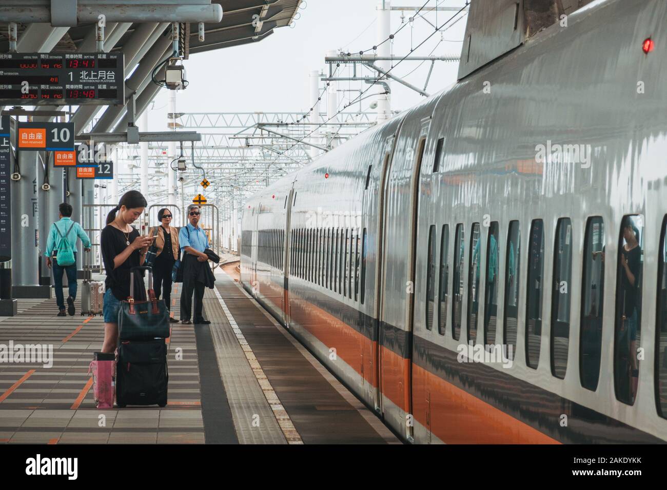 Une femme vérifie son téléphone lors de l'attente sur la plate-forme d'un Taiwan High Speed Rail bullet train, à la gare de Tainan, Taiwan Banque D'Images