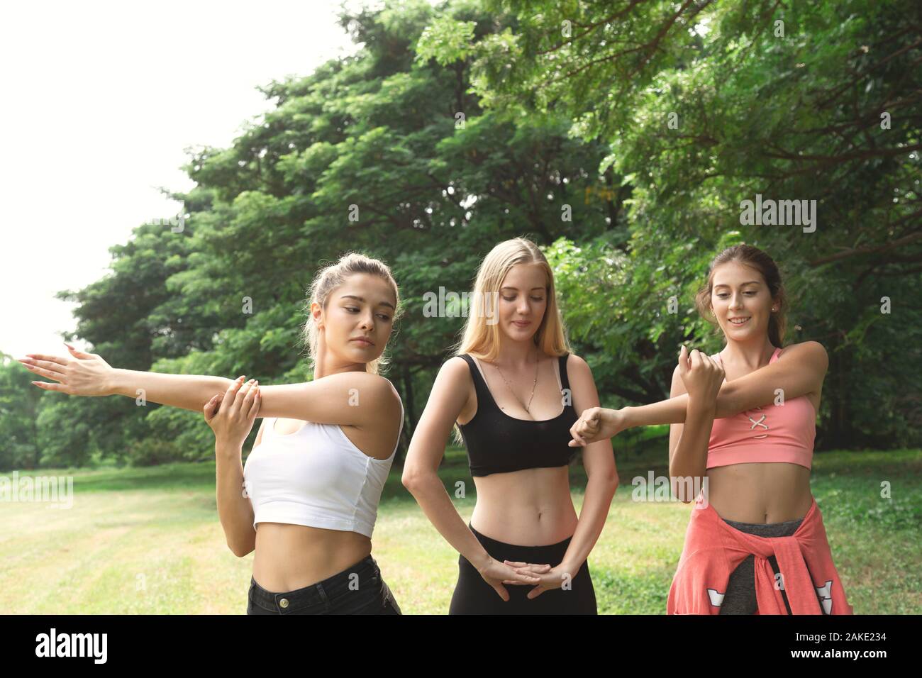 Heureux sain trois belles jeunes adolescents femme et le stretching pour l'échauffement avant l'exercice dans le parc. Fitness, sport, amitié et Banque D'Images