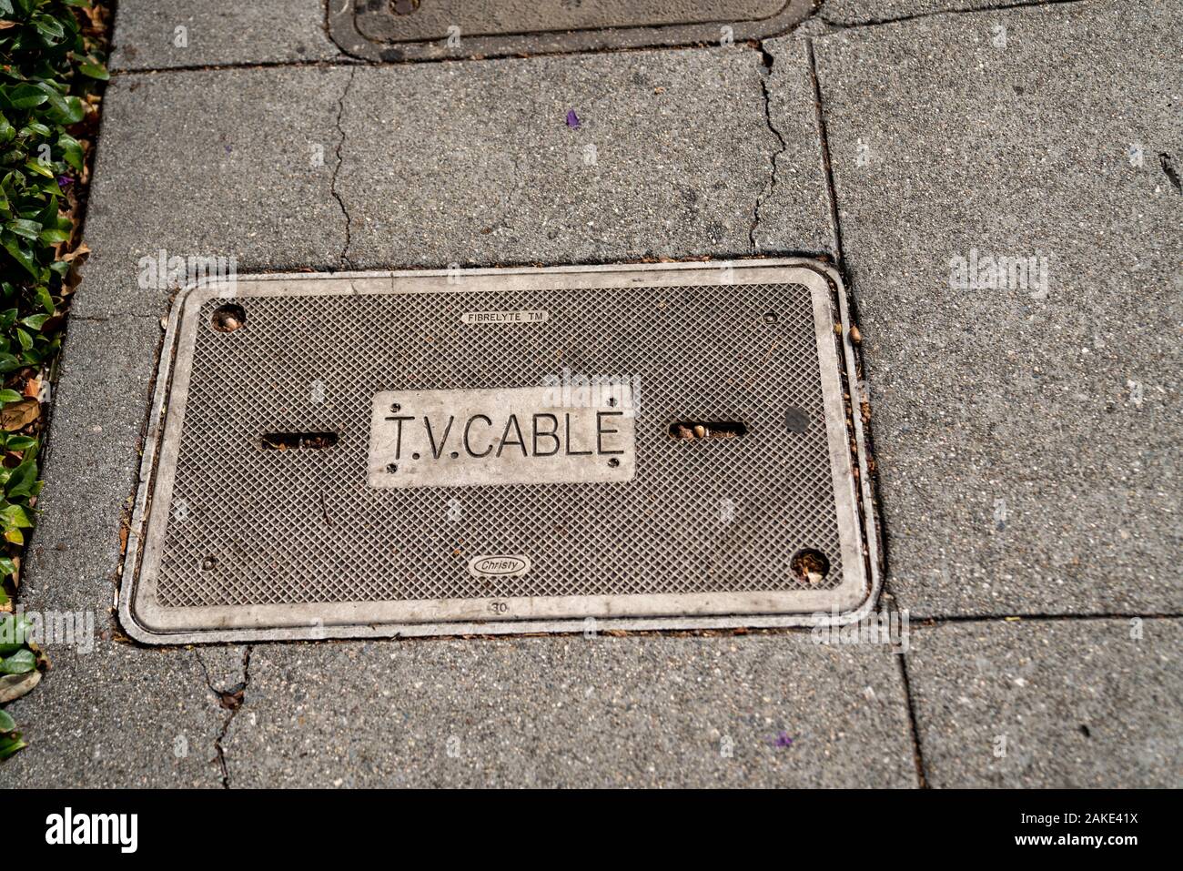 Trappe de service pour la télévision par satellite et câble sur trottoir Banque D'Images