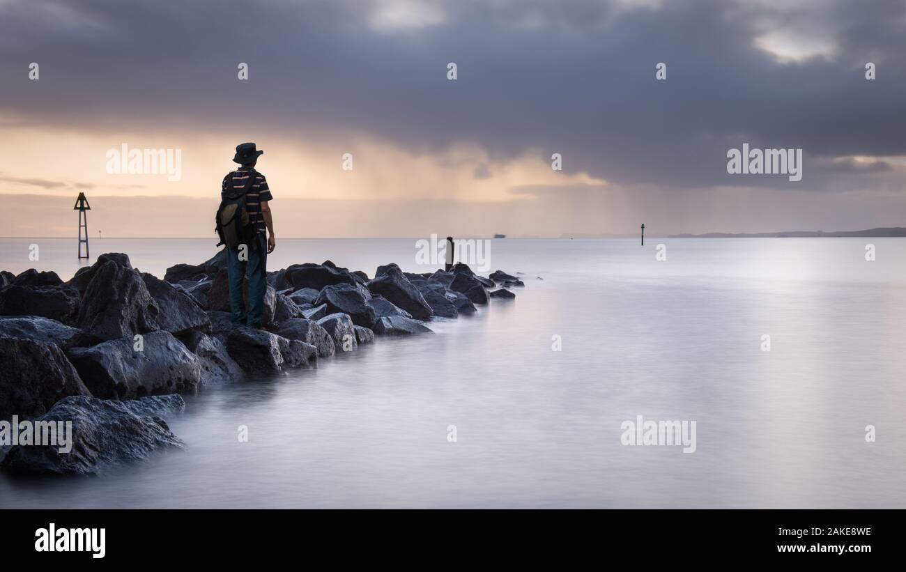 Regarder le lever du soleil à Milford, Auckland, Nouvelle-Zélande Banque D'Images