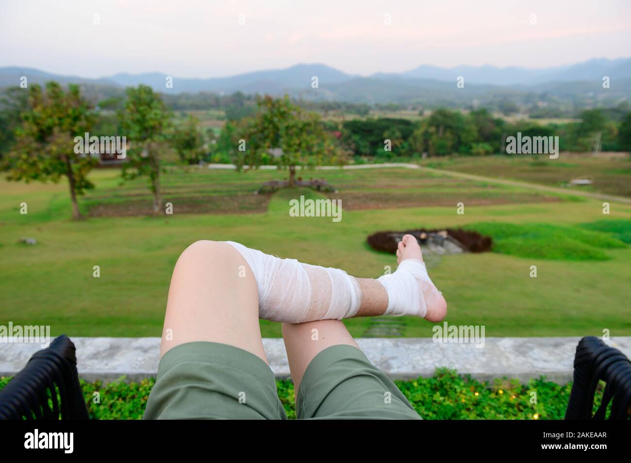 L'homme se reposer en plein air, sur une pelouse avec des jambes de bandage Banque D'Images