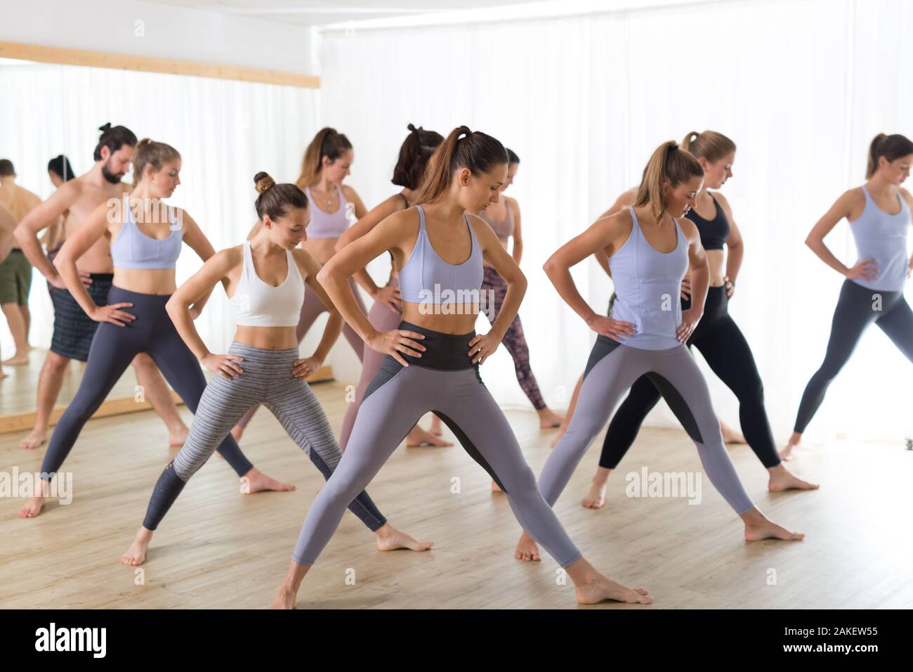 Groupe de jeunes gens de attrayant sportive authentique studio de yoga, la pratique du yoga leçon avec instructeur. Mode de vie sain et actif, working out in gym Banque D'Images