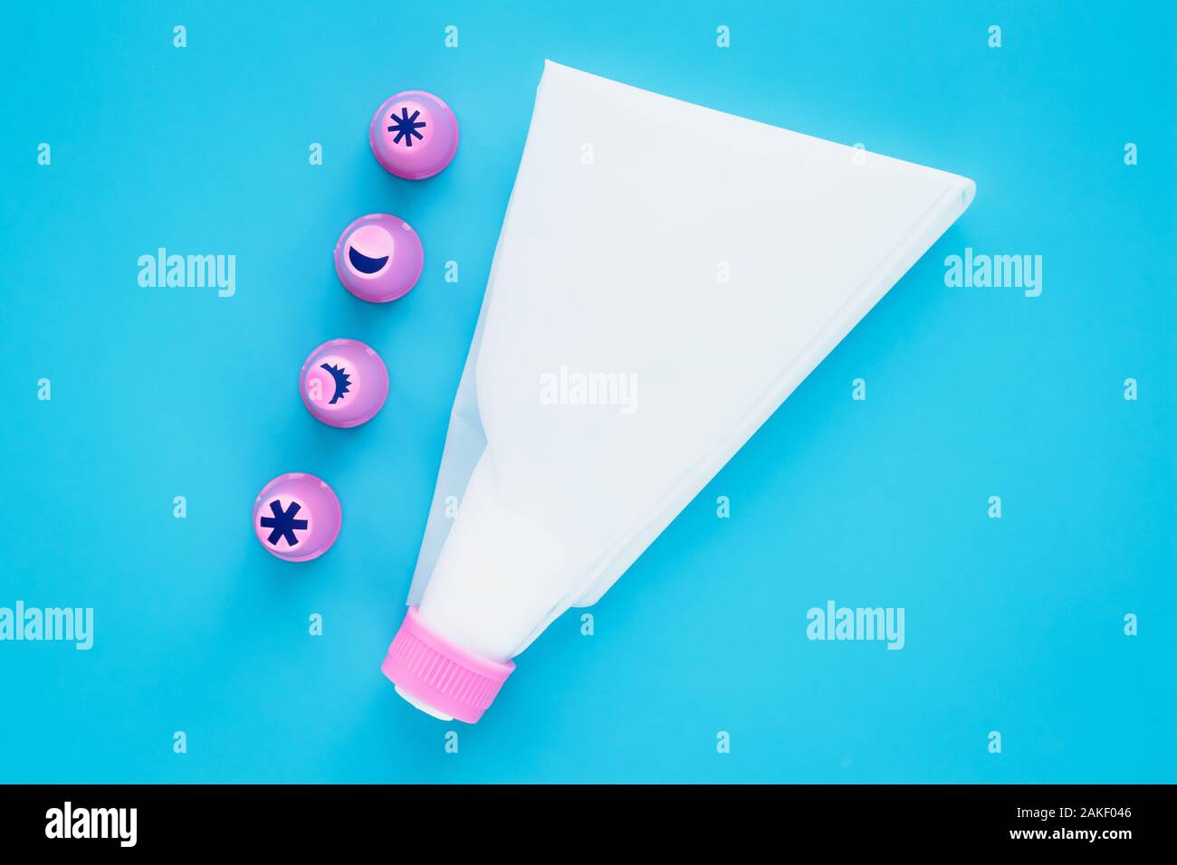 La poche à pâtisserie avec les buses sur fond bleu. Outils de décoration de gâteau Banque D'Images