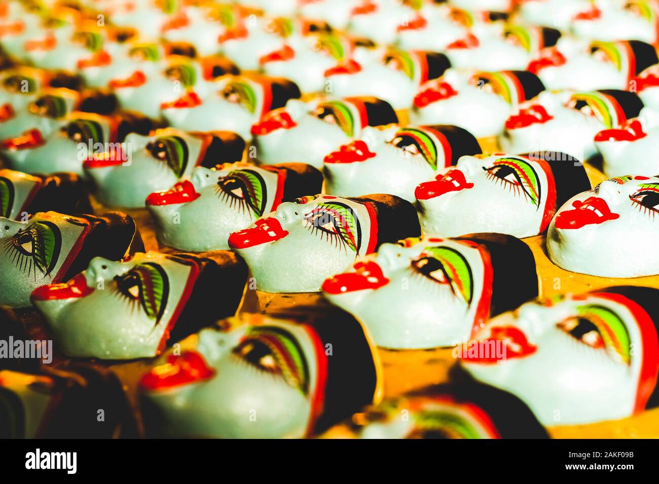 Masques faciaux traditionnels colorés disposés en rangées pour la vente de festival au marché artisanal Banque D'Images