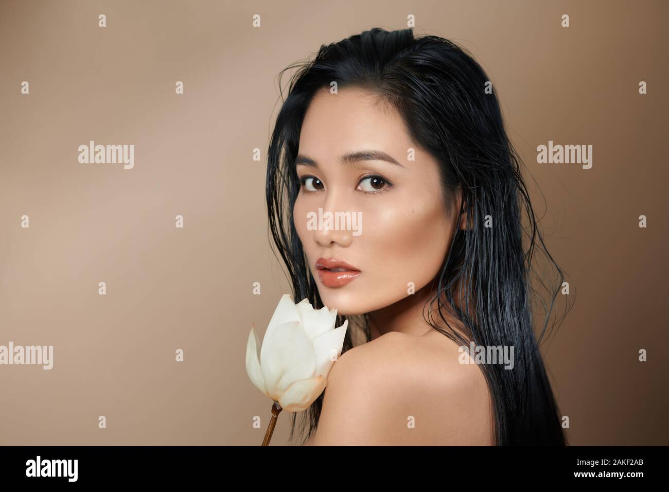 Les jeunes belles femmes asiatiques holding boutons de lotus séchées sur fond beige Banque D'Images