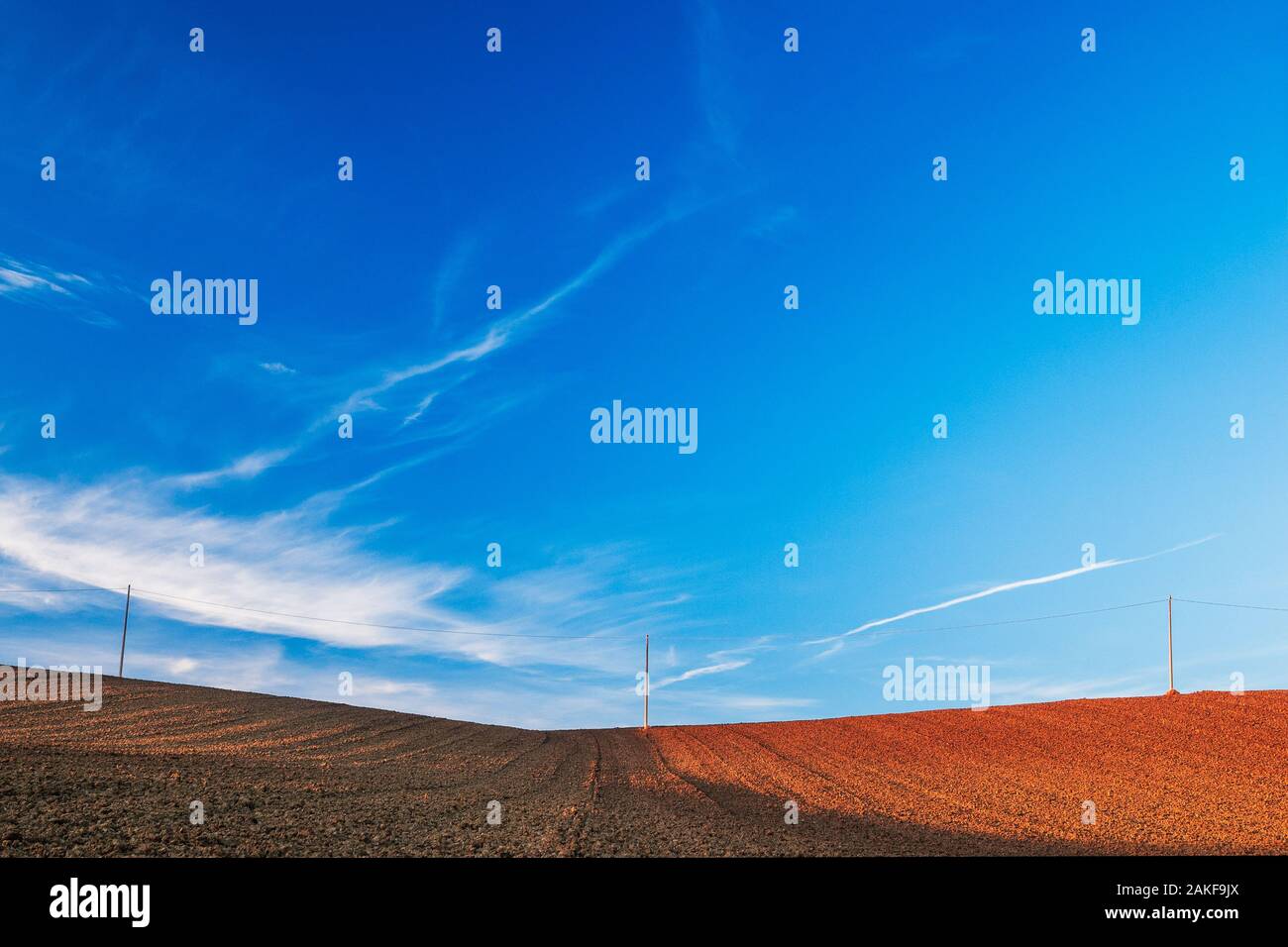Une ligne électrique sur un champ labouré, sous un magnifique ciel bleu Banque D'Images