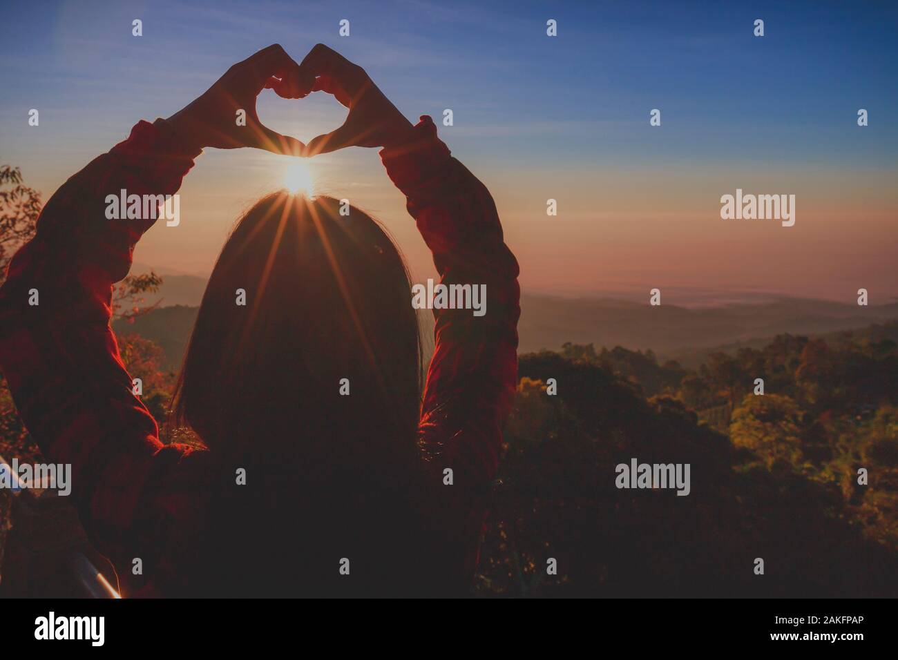 Une fille thaïe faisant symbole coeur avec ses mains au-dessus de la tête au lever du soleil Banque D'Images