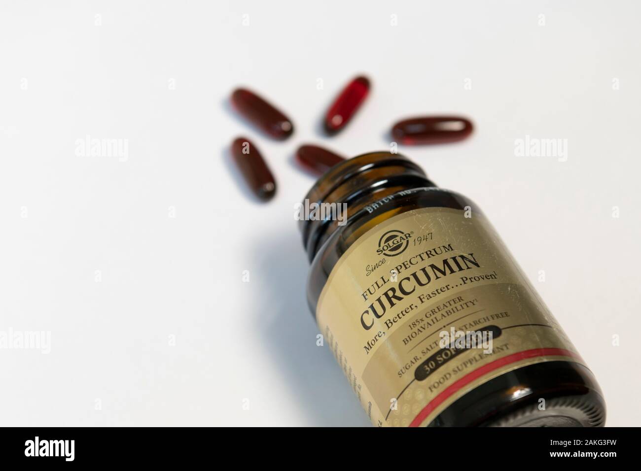 La curcumine curcuma ou mediical caspules échappe d'une bouteille sur un fond blanc Banque D'Images