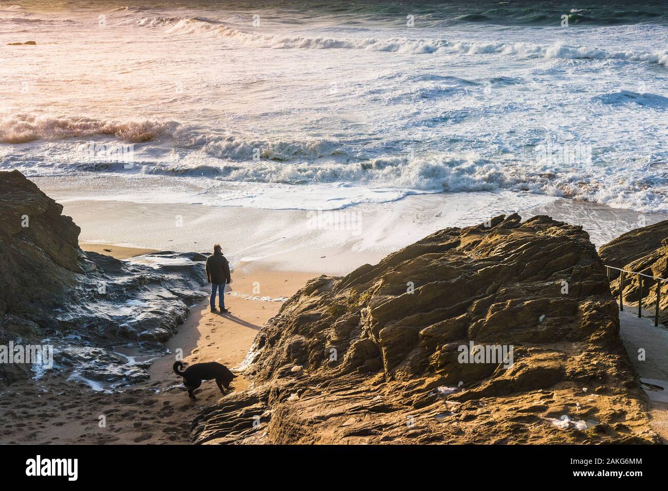 Un homme debout sur la plage et regarder les vagues dans une mer agitée à peu dans Fistral Newquay en Cornouailles. Banque D'Images