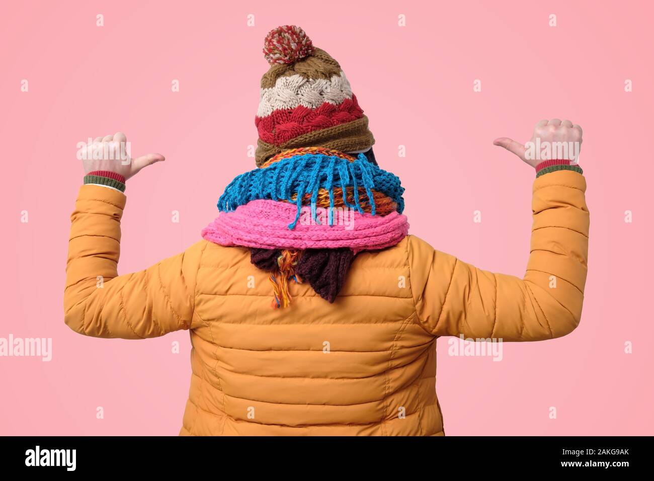 Jeune homme en hiver chapeaux et écharpes avec les doigts pointant sur lui-même. Je suis prêt pour de grandes gelées. Vue arrière Banque D'Images