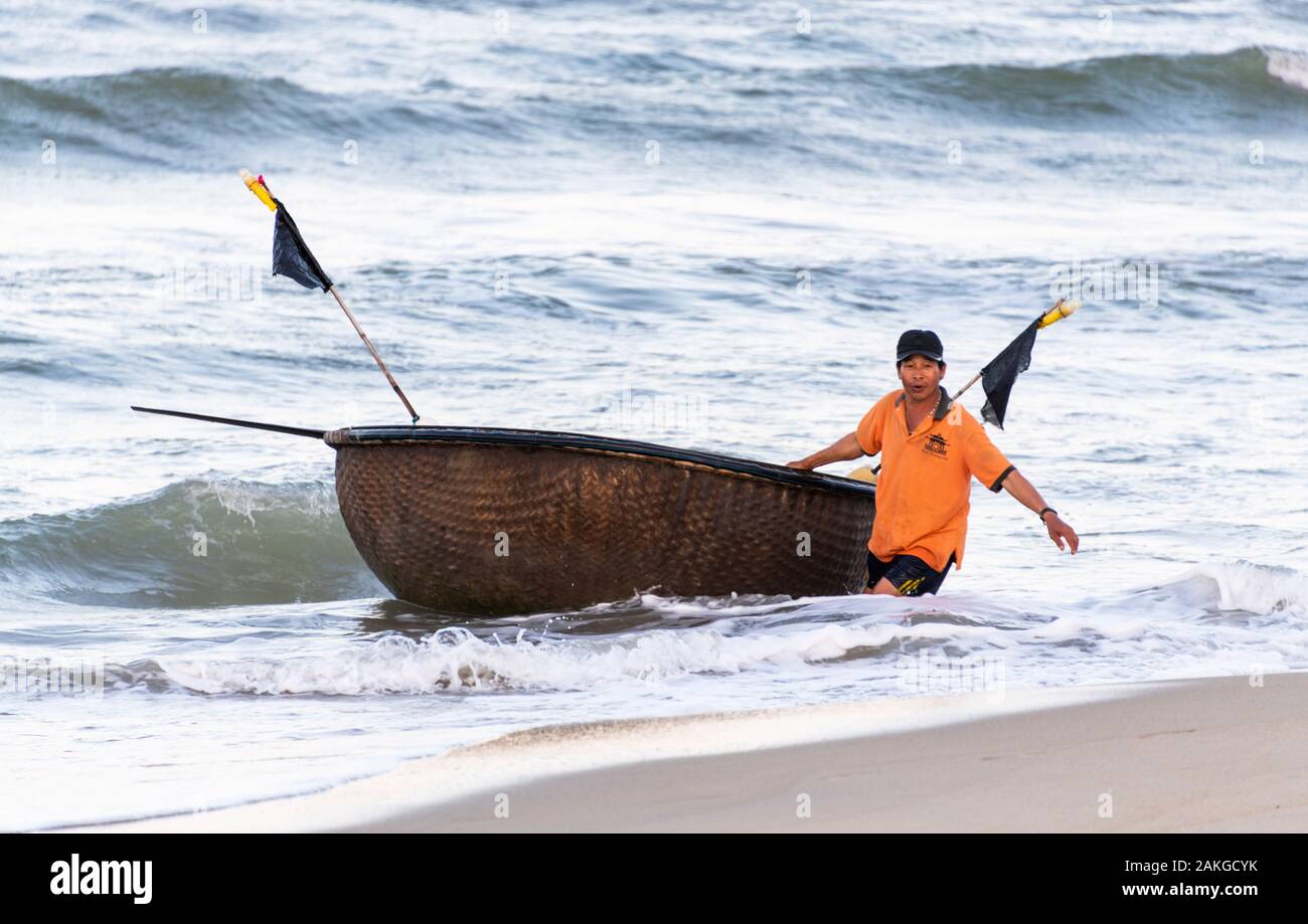 Pêcheur tirant le bateau de la coracle de la mer, Hoi An Vietnam Banque D'Images