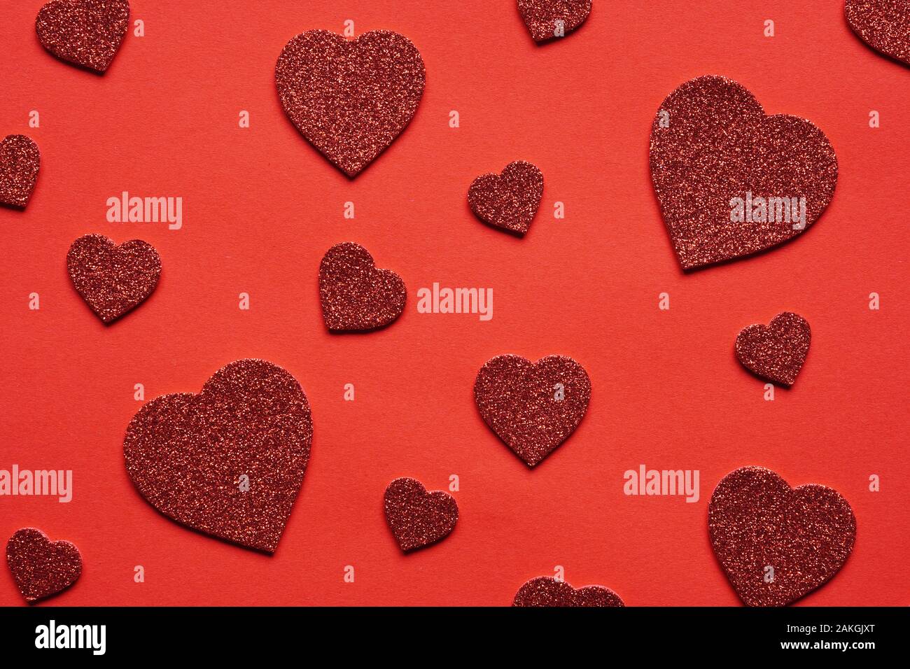 Sur le thème de l'amour fond rouge avec des paillettes en forme de coeur coeurs en différentes tailles - saint valentin ou un mariage concept Banque D'Images
