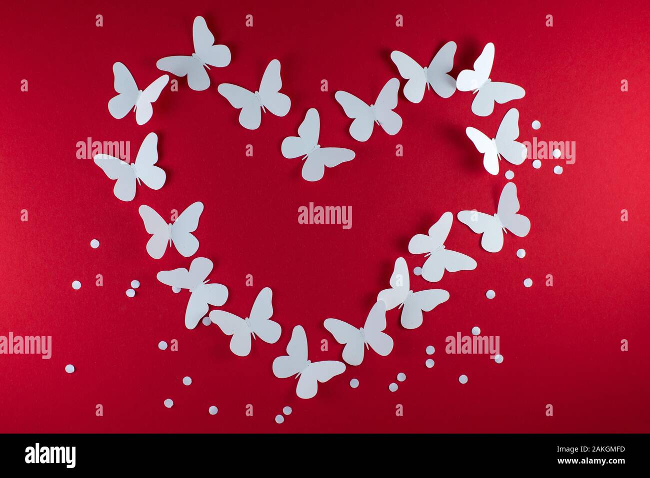 Papillons de papier blanc en forme de coeur sur fond rouge pour la St Valentin heureux jour. Banque D'Images