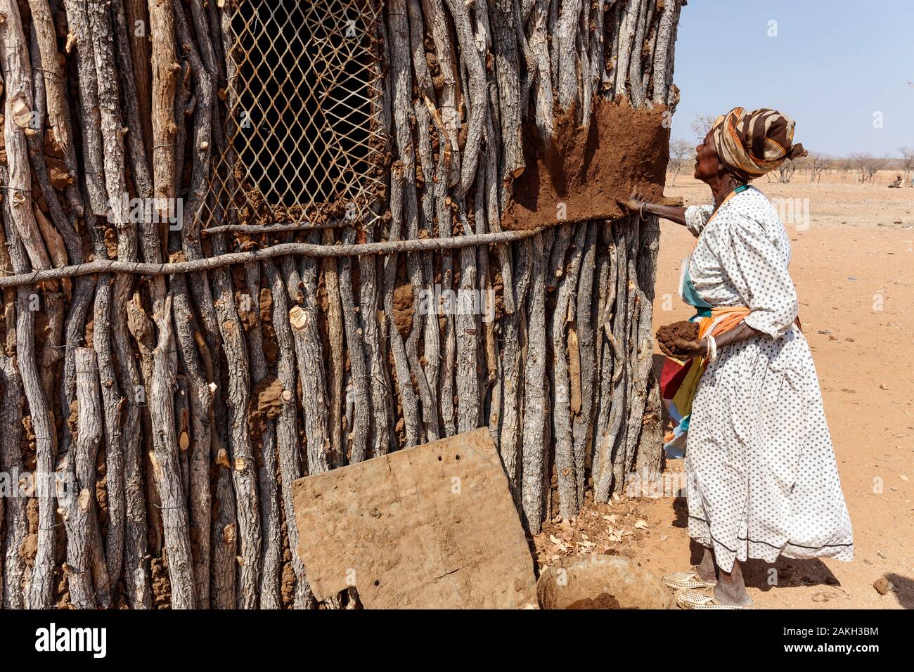 La Namibie, province de Kunene, Kamanjab, une femme Damara sa maison avec des murs de revêtement s/n Banque D'Images