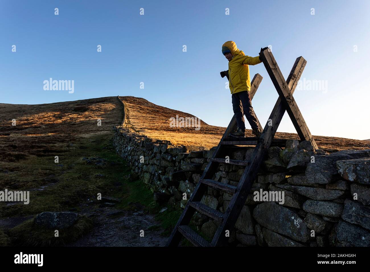 Montagnes et lacs de Mourne en Irlande du Nord, Royaume-Uni. Vue depuis le sommet de Slieve Loughshannagh, jeune garçon grimpant sur le mur sur les escaliers en bois Banque D'Images