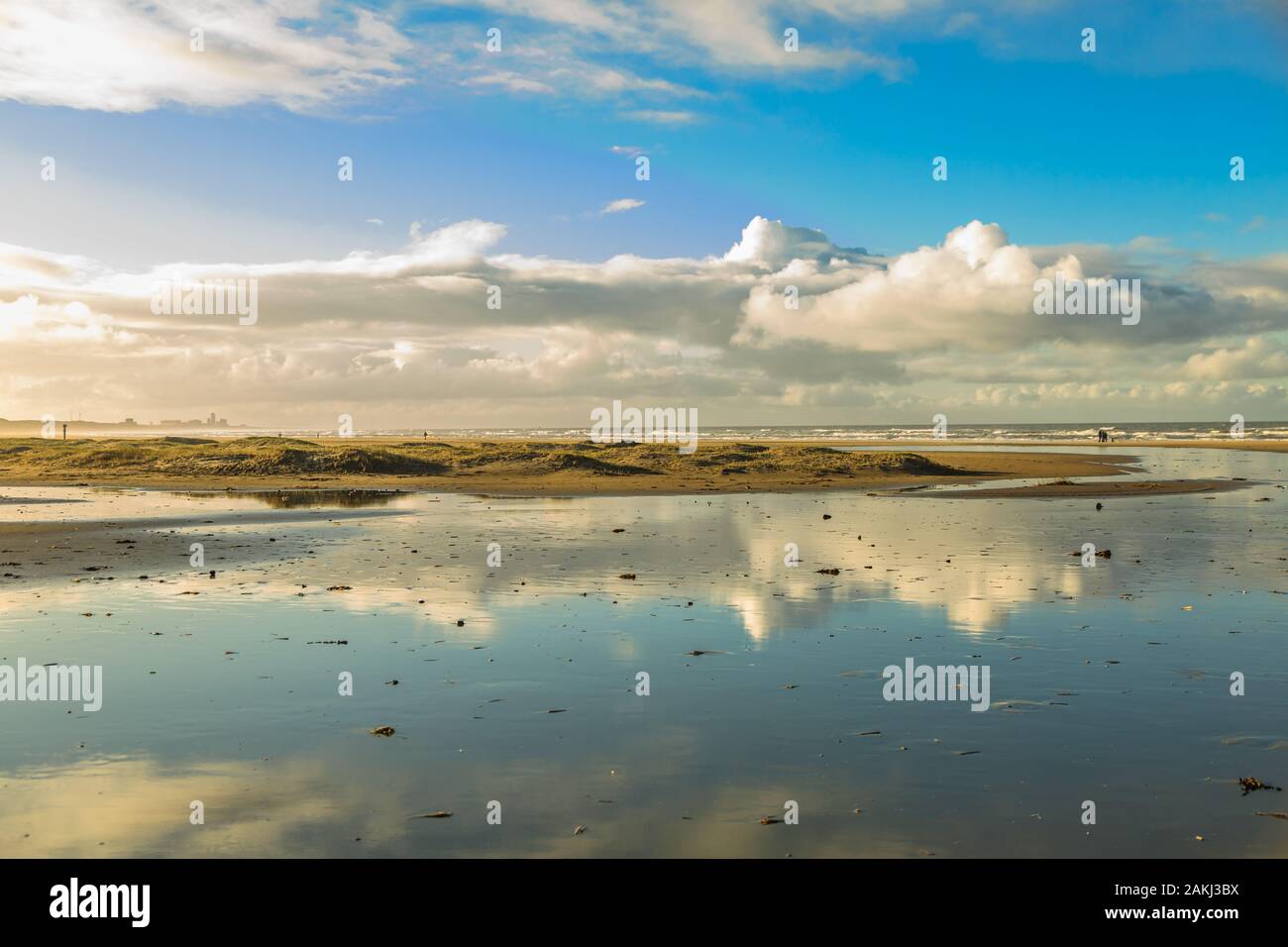 Lever du soleil plage de la mer du Nord à IJmuiden vue vers Zandvoort avec la marée basse et début de la formation de dune sur la plage contre l'arrière-plan de nuages et l'horizon Banque D'Images