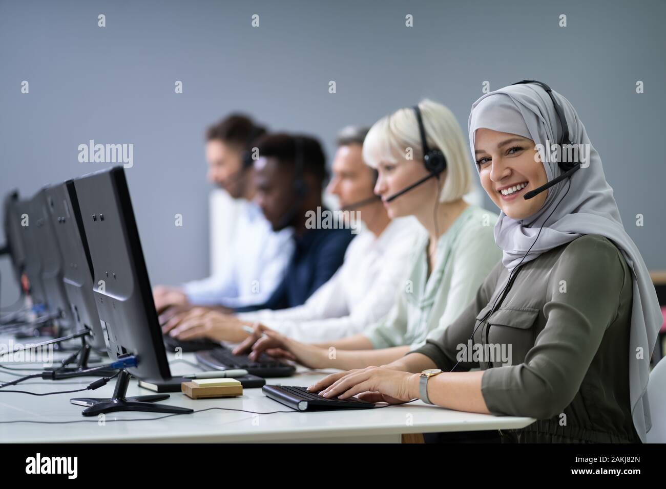 L'agent des services à la clientèle féminine positive avec casque de travail dans un centre d'appels Banque D'Images