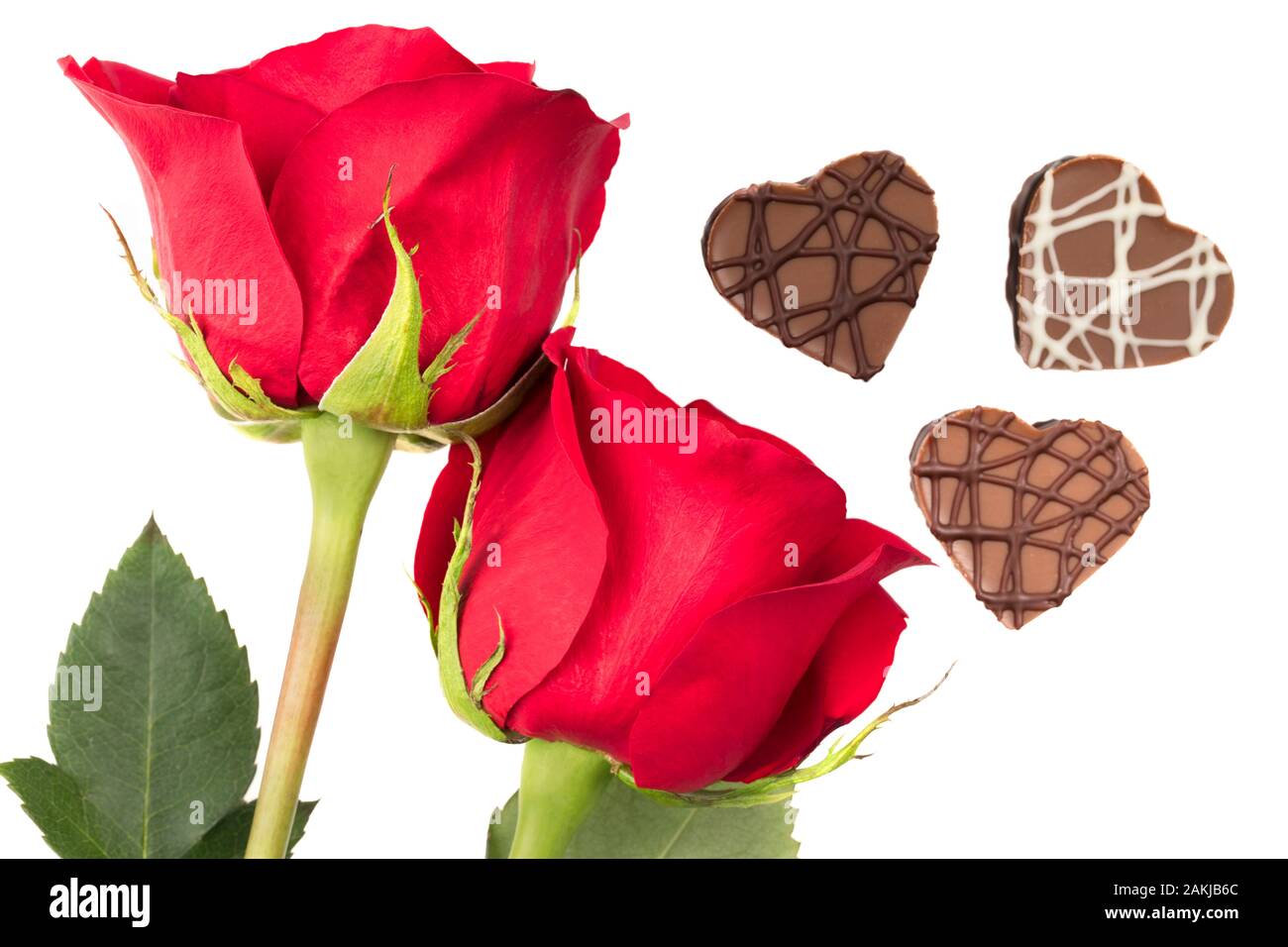 Des roses rouges et des chocolats en forme coeur isolé sur fond blanc Banque D'Images