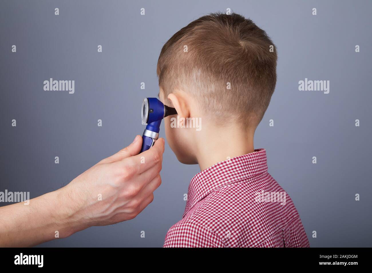 Médecin examinant l'oreille d'un garçon avec un otoscope. Oreille d'examen  ORL avec otoscope sur fond gris Photo Stock - Alamy