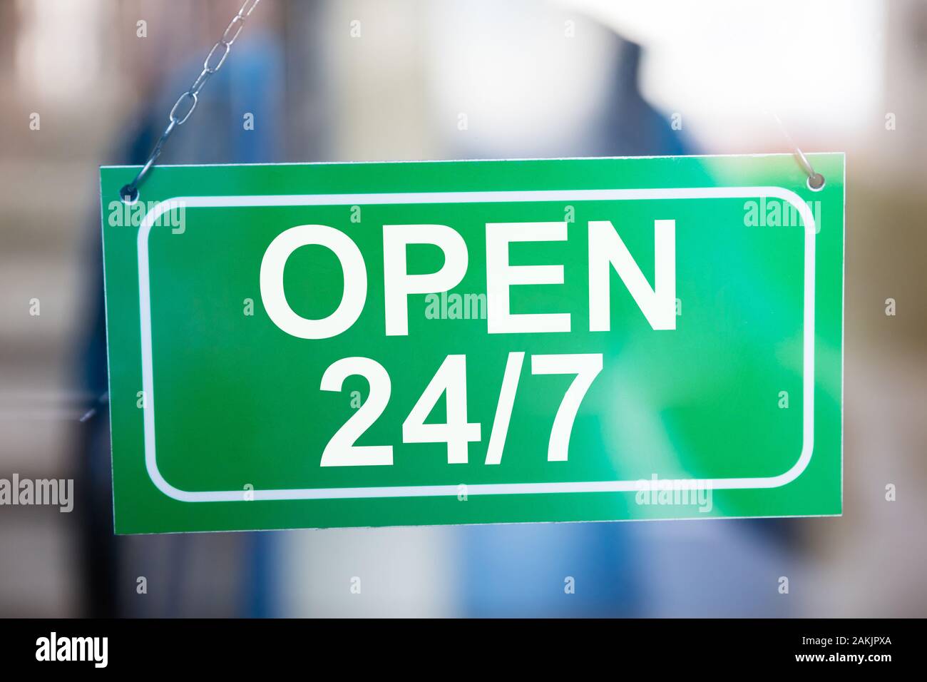 Close-up of Green ouvert 24h/24 Information Board accroché sur la porte de verre Banque D'Images