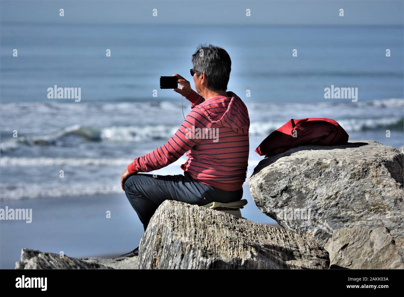 Homme asiatique senior faisant des photos de ses enfants surfant Dans les basses vagues de l'océan Pacifique juste au nord De Ventura Banque D'Images