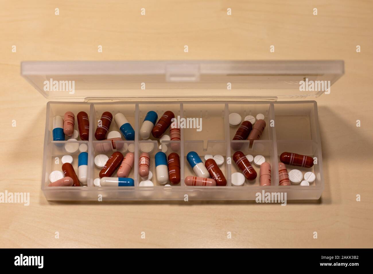 Comprimé en plastique boîte contenant des médicaments pharmaceutiques sous forme de comprimés, comprimés et gélules sur un tableau de bouleau Banque D'Images