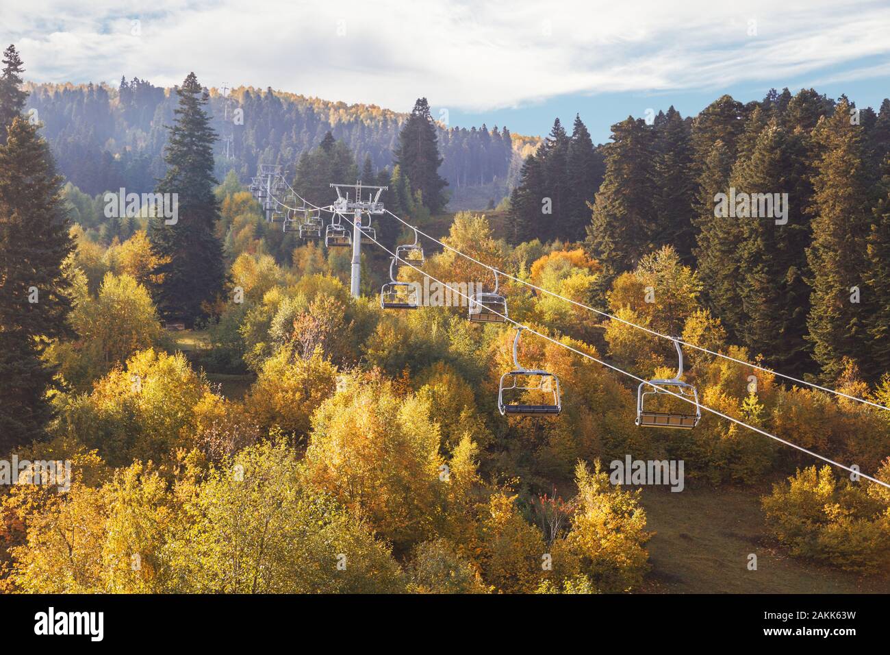 Station de ski en automne. Télésiège vide au-dessus des arbres à feuillage jaune. Paysage de montagne ensoleillée d'automne. La Géorgie, Svaneti Banque D'Images