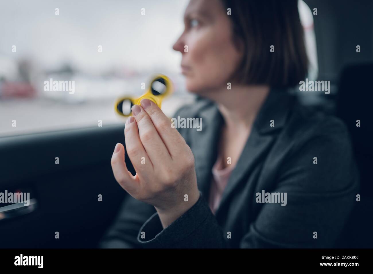 Businesswoman jouant avec fidget spinner dans la voiture pendant qu'assis à l'arrière du véhicule et se rendre à son travail, selective focus Banque D'Images
