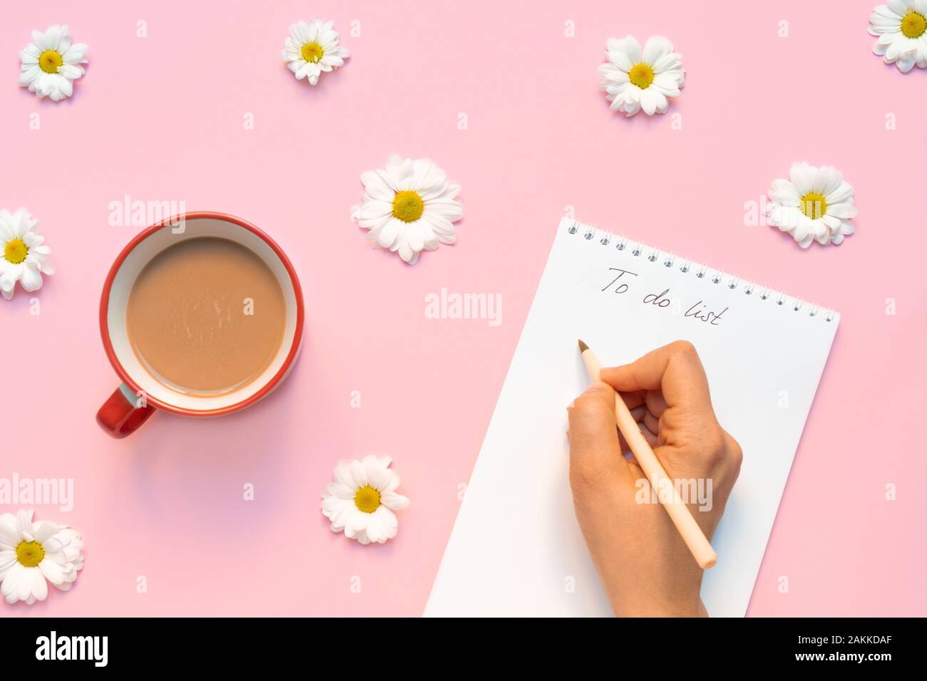 Composition florale avec tasse de café le matin et la main d'une femme tenant le stylo et écrivant "À faire liste" Banque D'Images