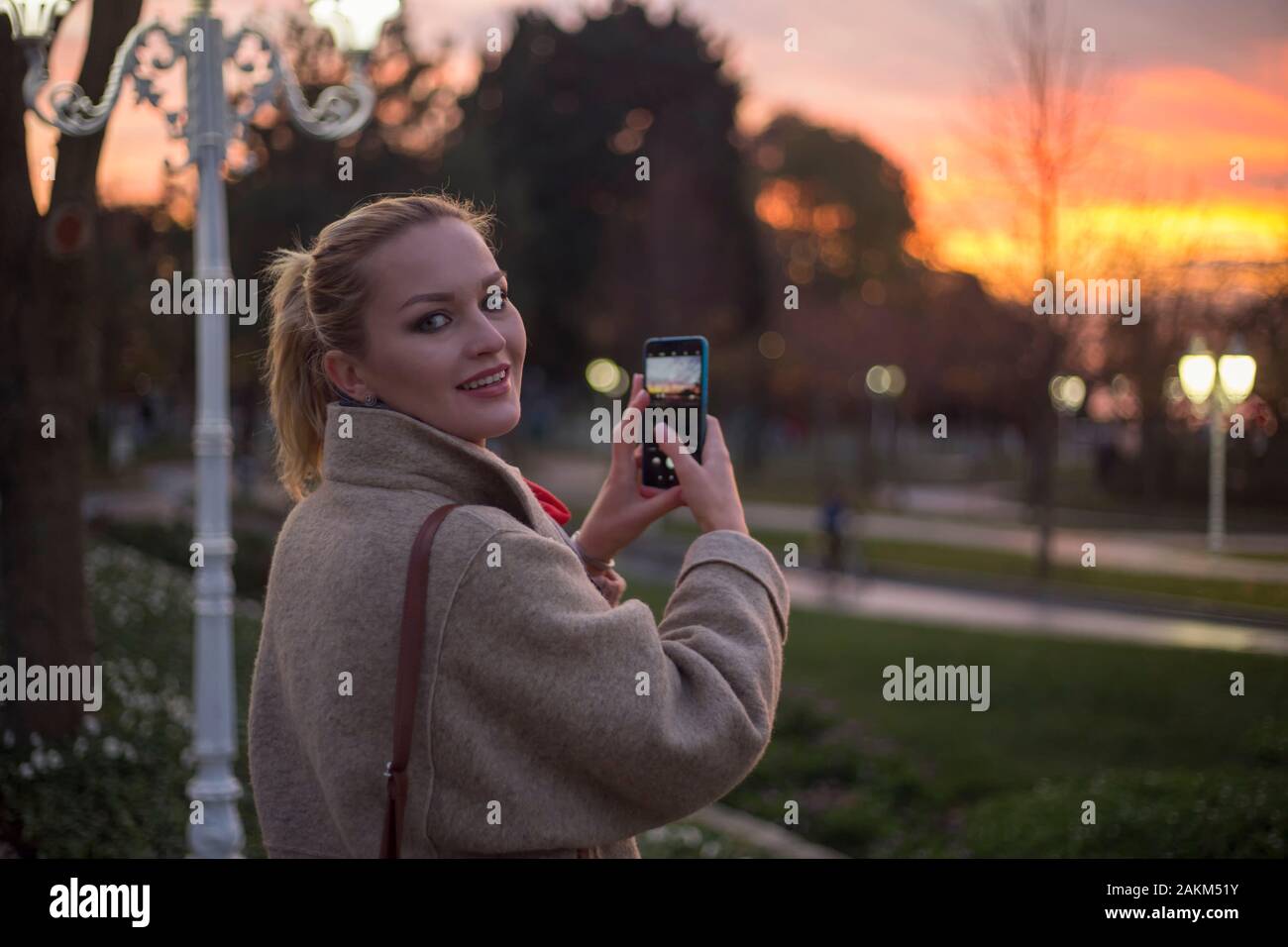 Jeune femme russe prend photo avec téléphone, au coucher du soleil Banque D'Images