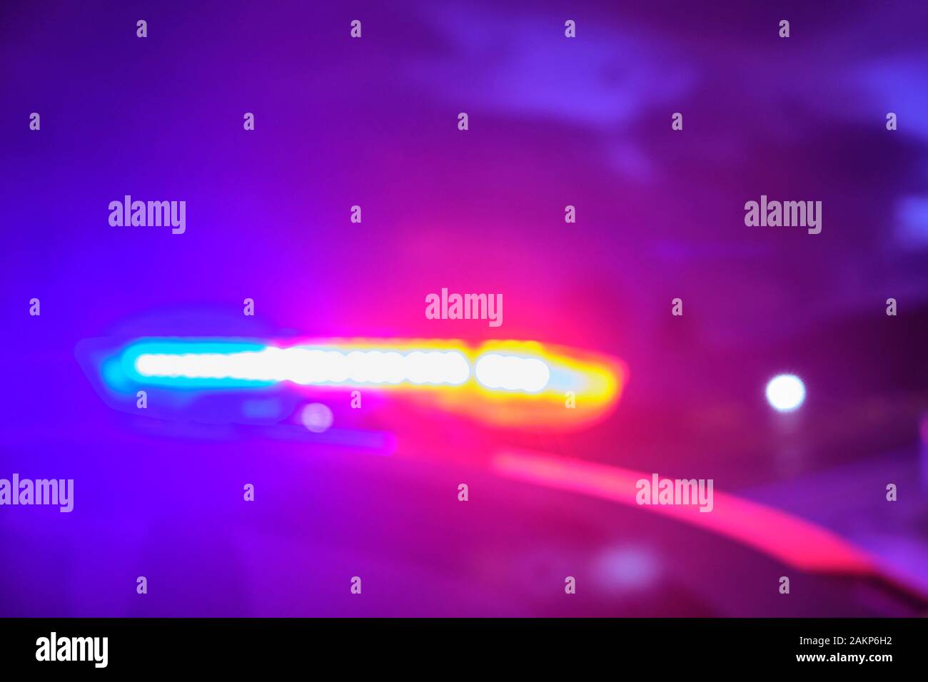 Voiture de police des lumières clignotantes dans la nuit au point sélective floue. Banque D'Images