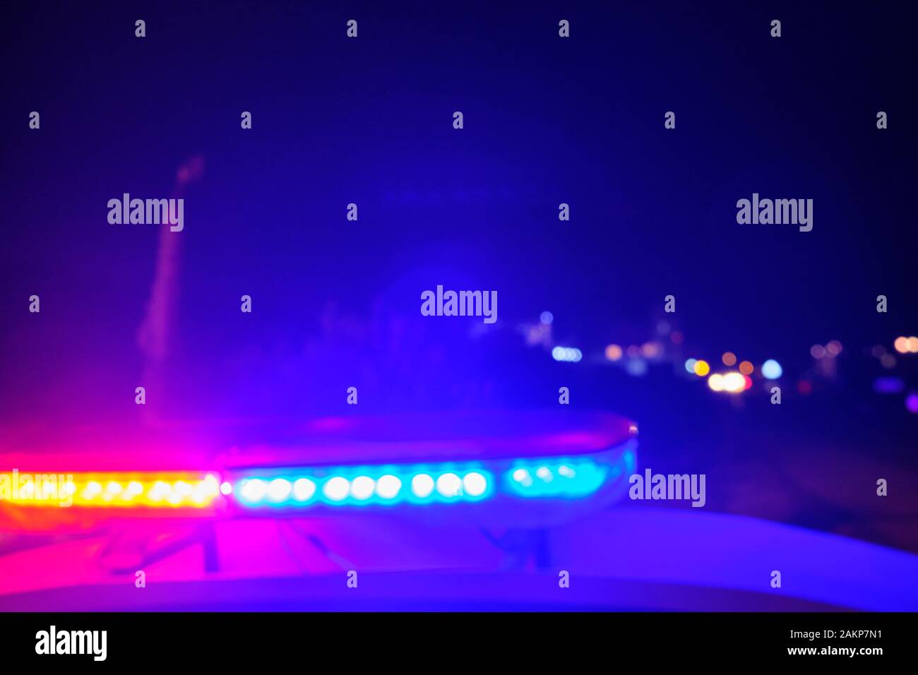 Voiture de police des lumières clignotantes dans la nuit au point sélective floue. Banque D'Images