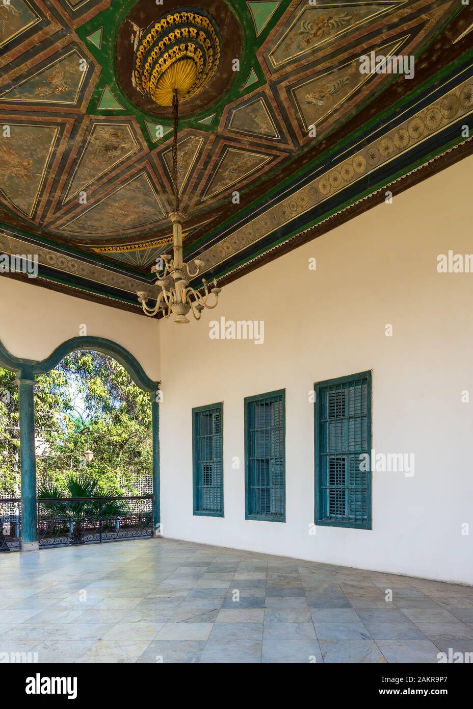 Terrasse couverte avec plafond peint décoré, volets de fenêtre verte et sol en marbre clôturé avec clôture en métal forgé en été ensoleillé Banque D'Images