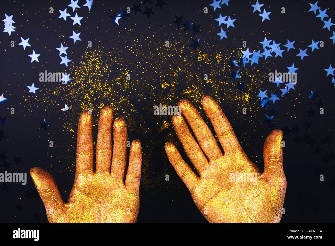 De belles mains dans la peinture d'or sur fond noir fastive close up Banque D'Images