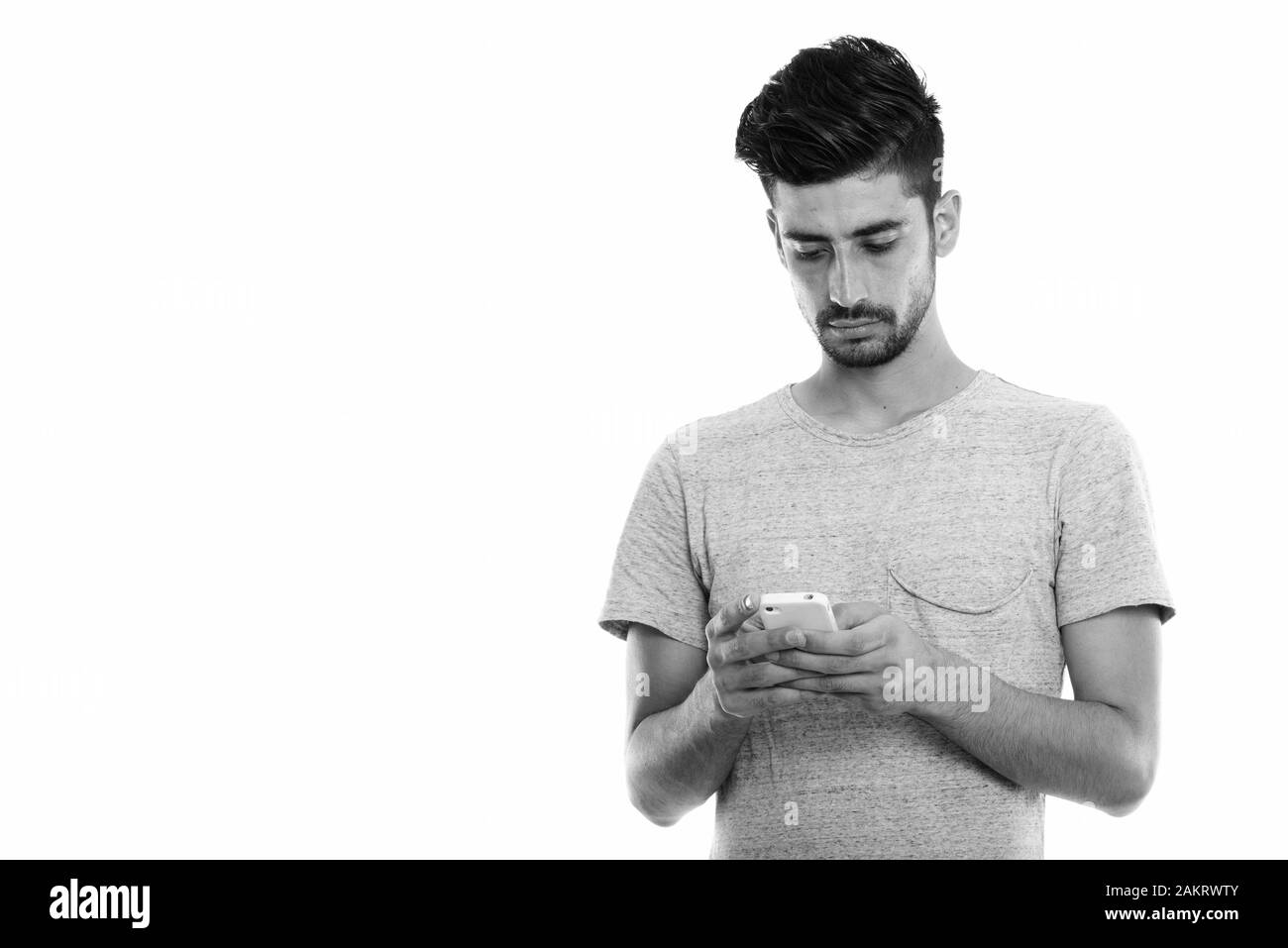 Studio shot of young man using mobile phone persan Banque D'Images