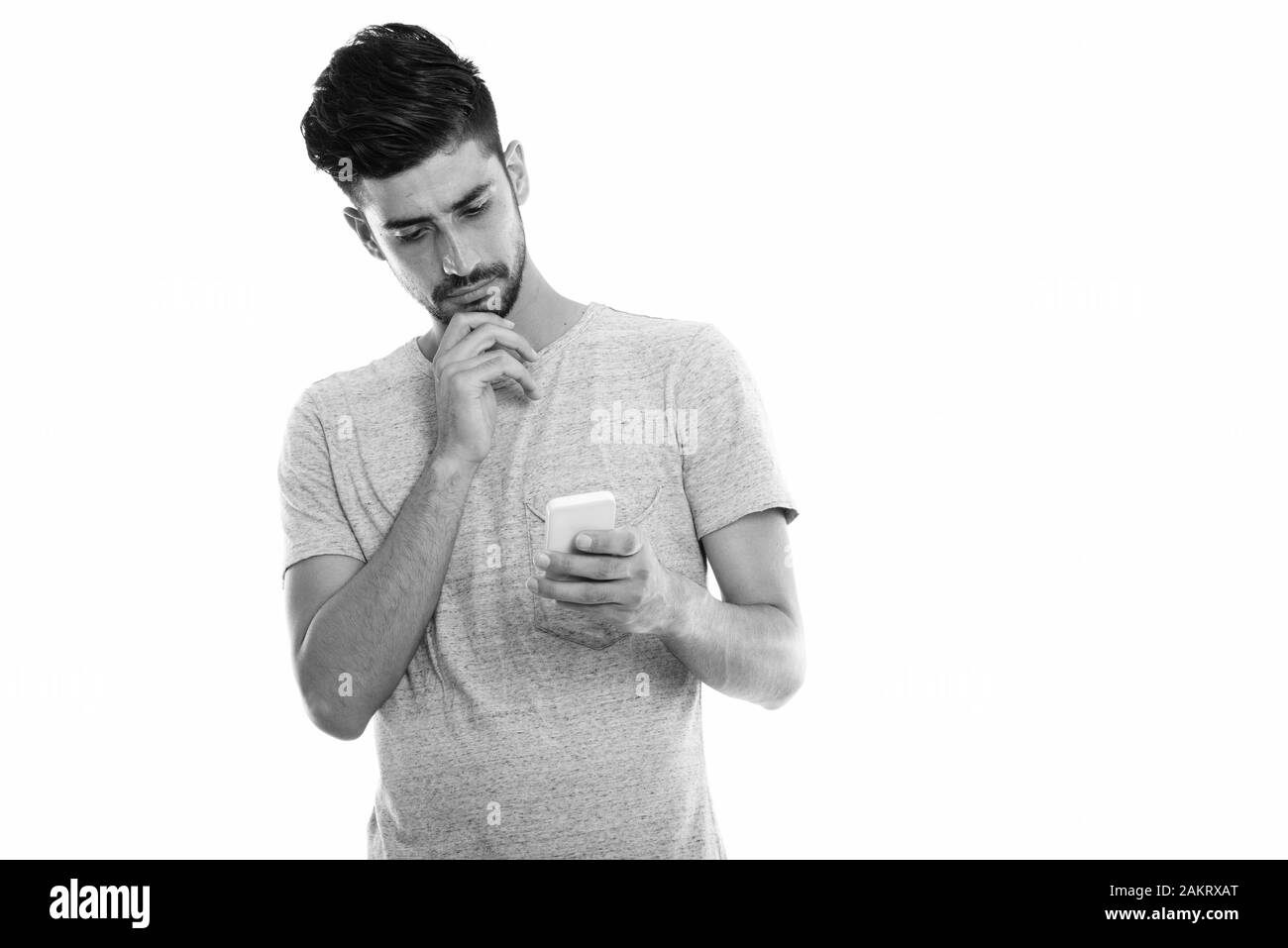 Studio shot of young man using mobile phone persan en pensant Banque D'Images