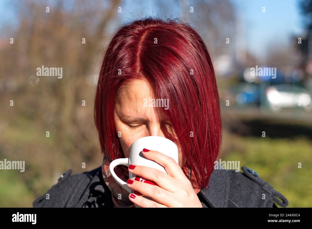 Portrait de la jeune femme à poil rouge avec une tasse de café Banque D'Images