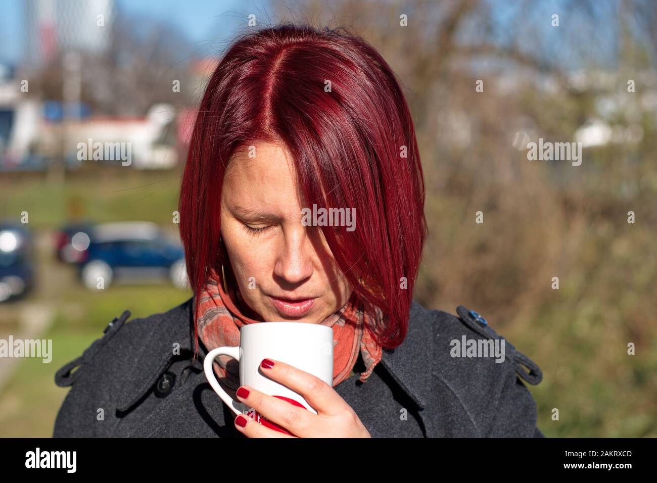 Portrait de la jeune femme à poil rouge avec une tasse de café Banque D'Images