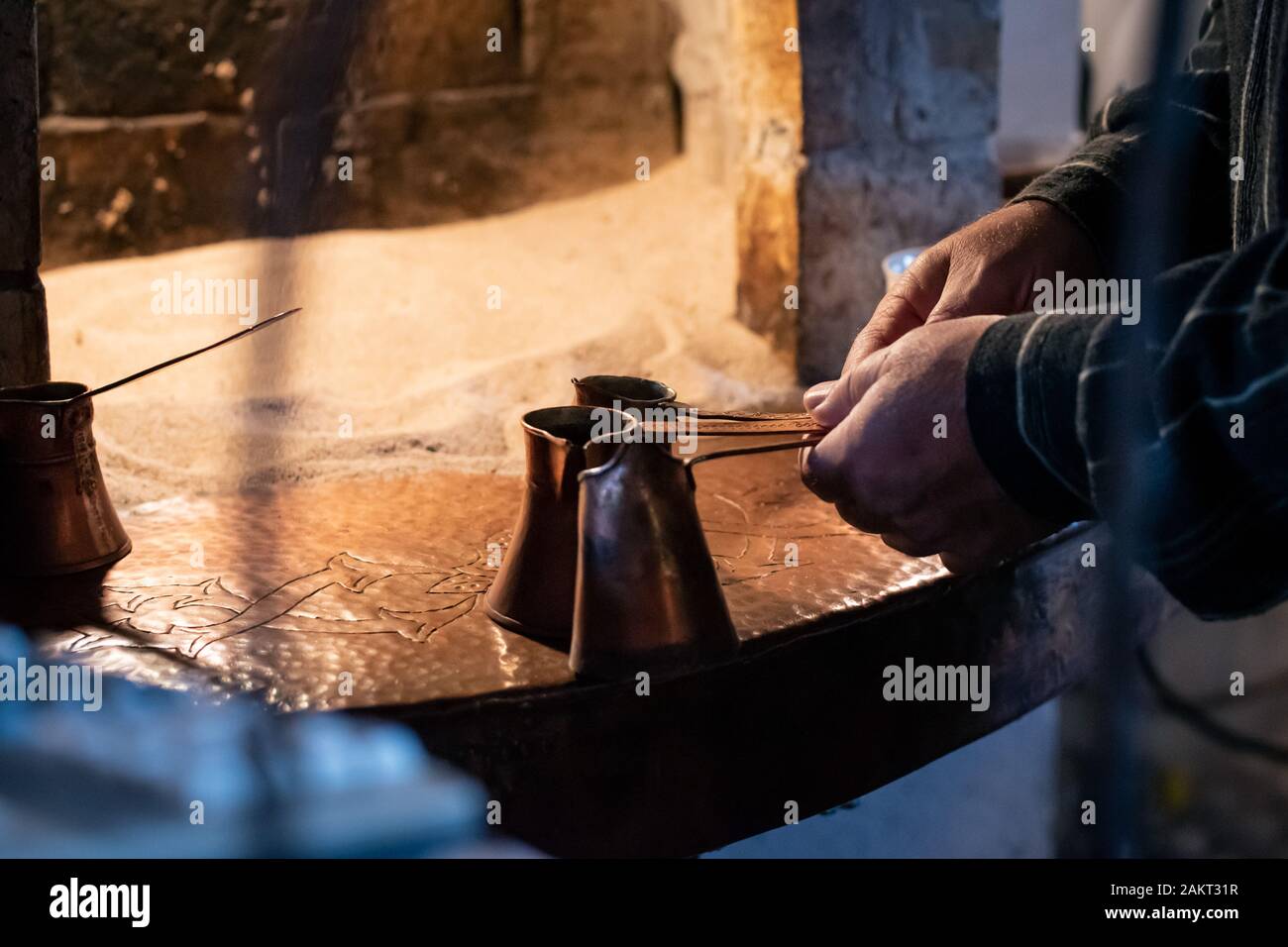 L'homme préparer le café turc traditionnel dans des pots en cuivre, préparé sur le sable chaud dans un four Banque D'Images