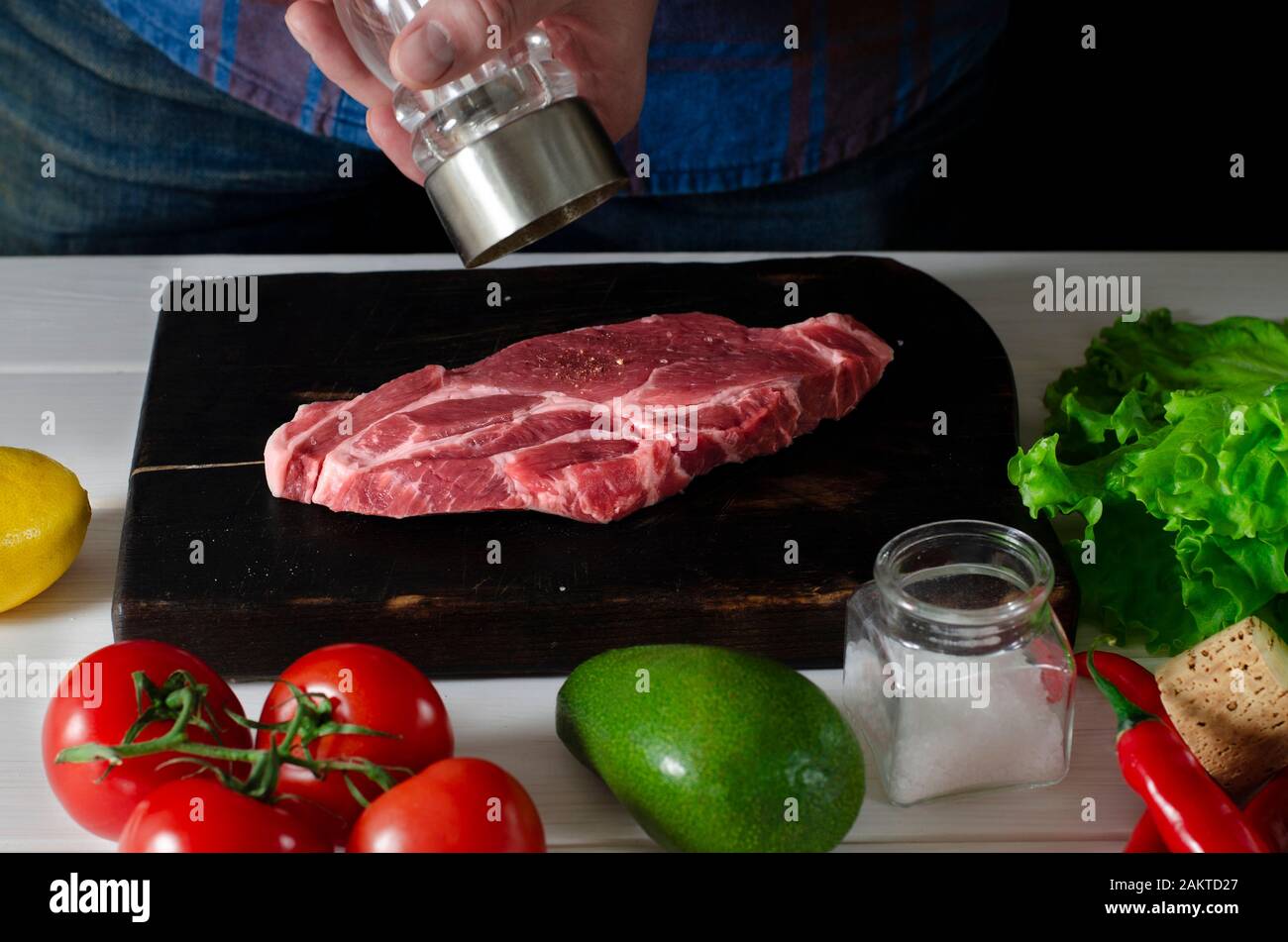 Les mains des hommes cuisinent un steak de viande qui se trouve sur un tableau de découpe Banque D'Images