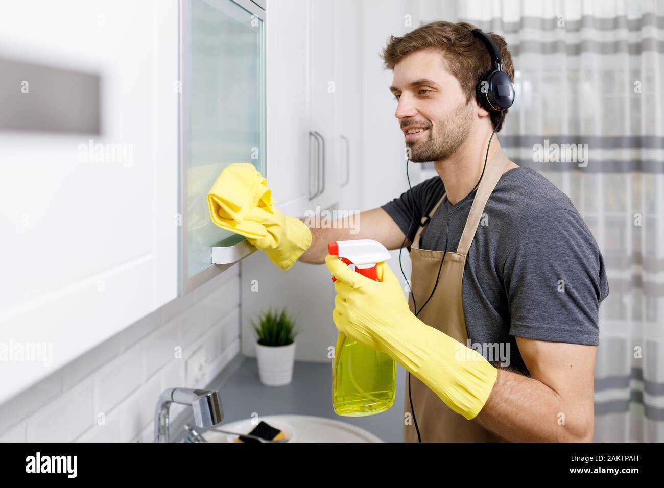 Jeune brunet lad nettoyer la cuisine avec impatience, à l'écoute de la musique Banque D'Images